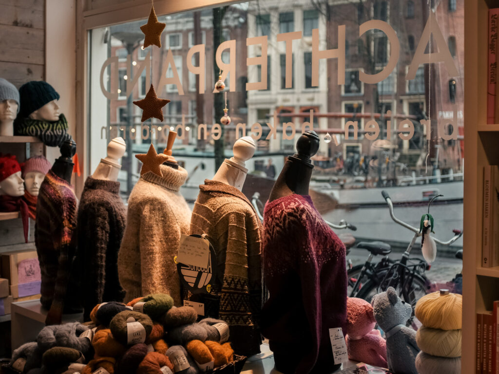 Wollen truien, garens en gebreide sterren voor het raam van handwerkwinkel Achterpand