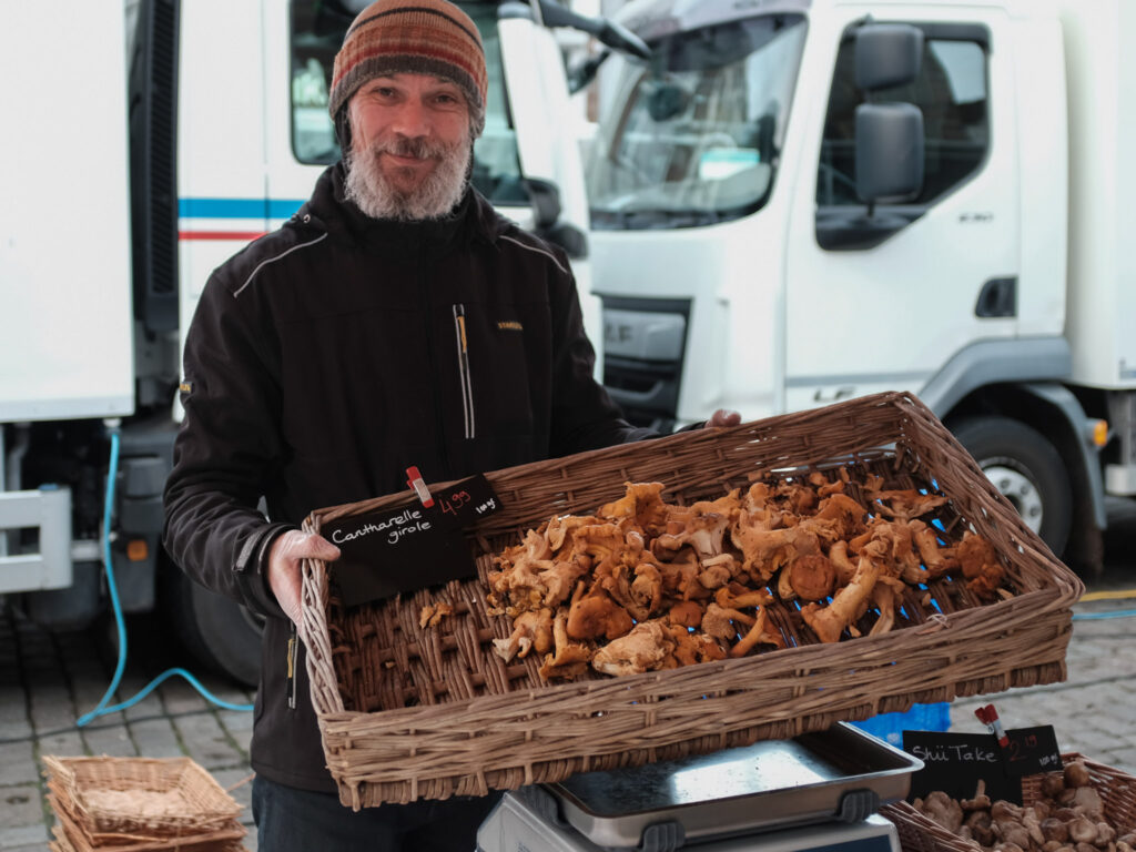 Marktkoopman van Boer Kabouter toont een mand verse cantharellen op de markt in Groningen