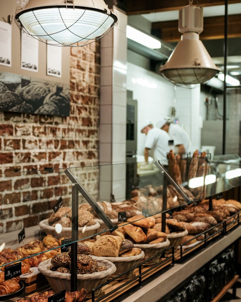 De vitrine van Broodje van Eigen Deeg vol brood en viennoiserie, met de bakkers aan het werk