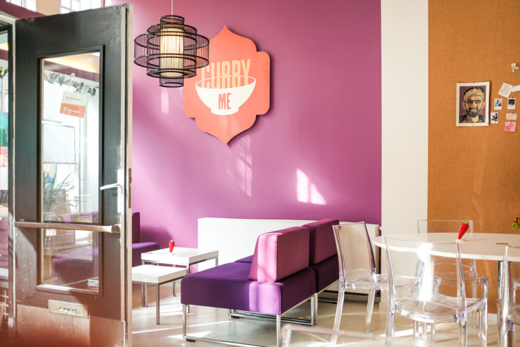 Het kleurrijke interieur van Curry Me, met banken en tafels