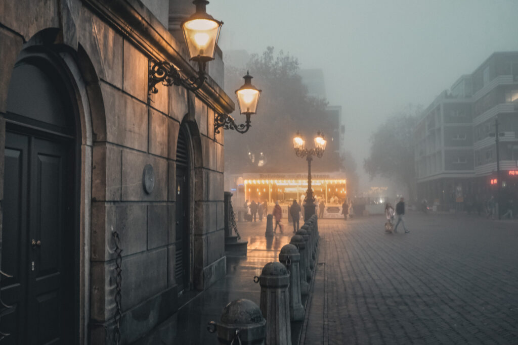 De mistige Grote Markt in Groningen met brandende gaslampen en een verlichte kraam