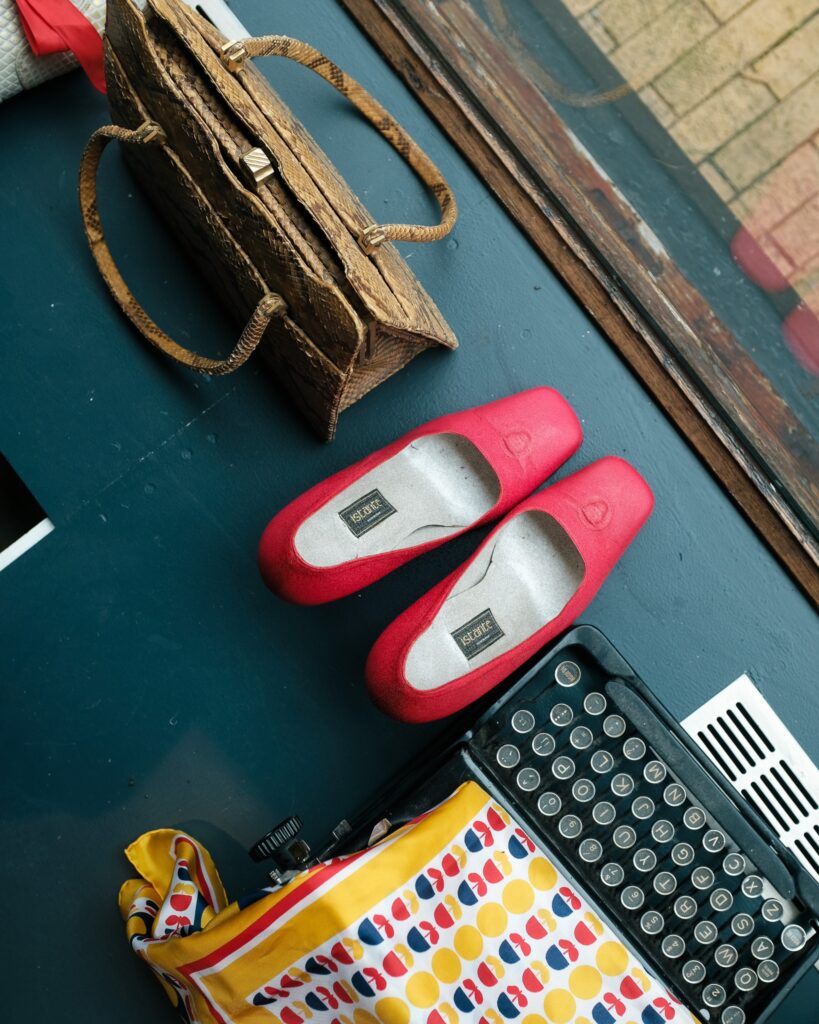 Rode schoenen en een vintage tas naast een oude typemachine