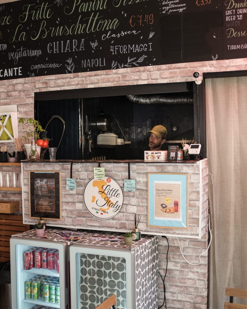De toonbank en open keuken van Little Italy, met het handgeschreven menu erboven