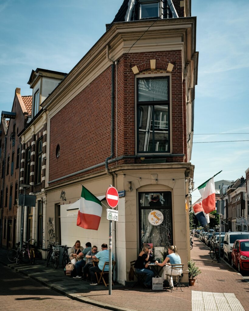 De smalle gevel van Little Italy met Italiaanse vlaggen en een klein terras
