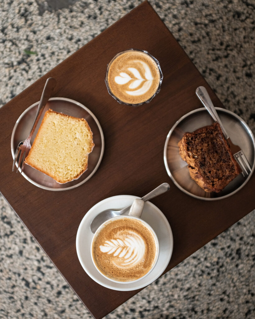 Twee koppen koffie en twee plakken cake op een houten tafel