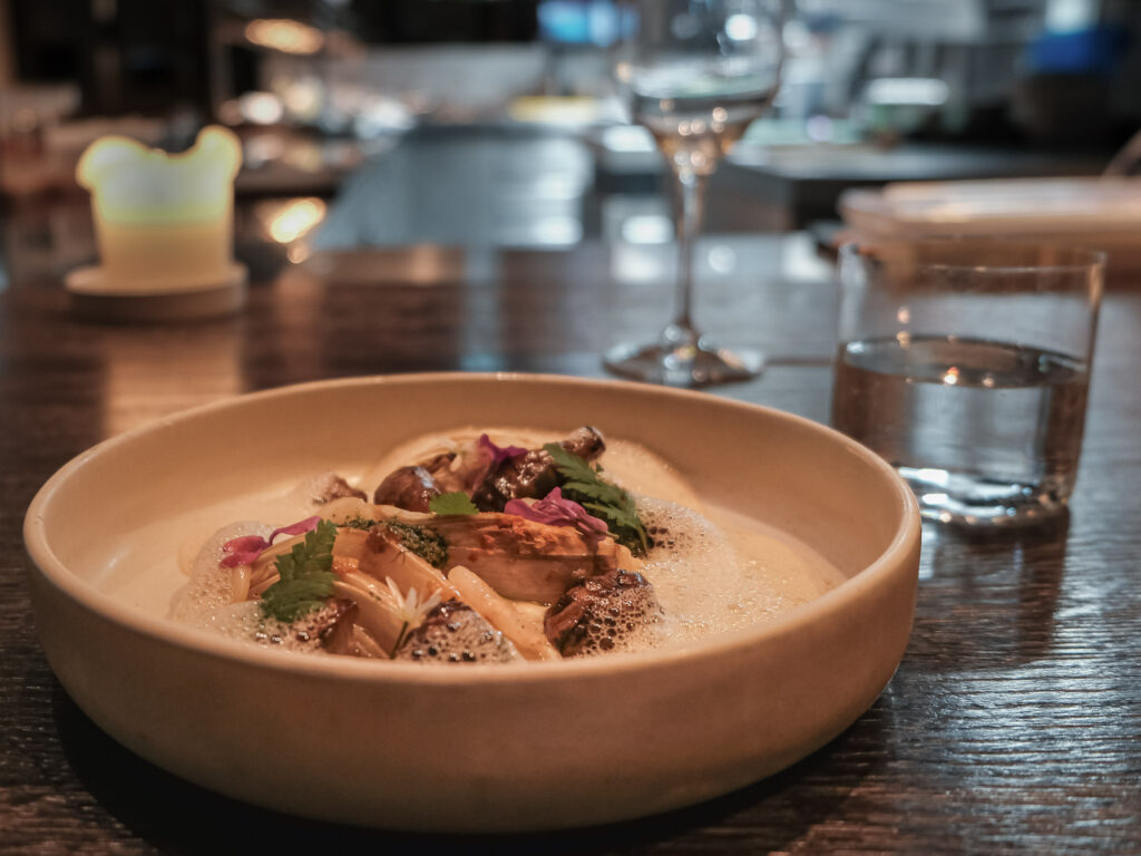 Gerecht op tafel bij restaurant Niemeijer, met kaarslicht en de open keuken op de achtergrond