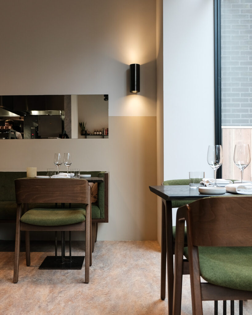 Het rustige interieur van Niemeijer met gedekte tafels en zicht op de keuken