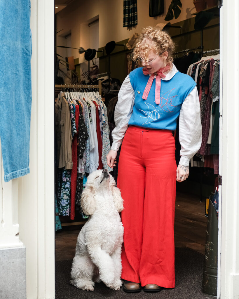 Een kleurrijke outfit en een witte hond in de deuropening van Sappho