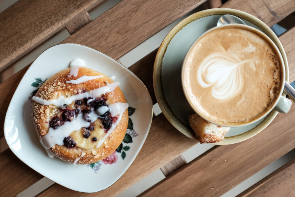 Cappuccino en een zoet broodje op de houten tafel bij Stoet