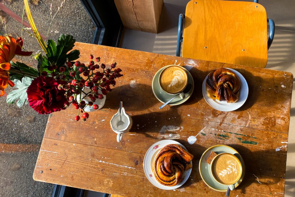 Koffie en kaneelbuns op een zonnige houten tafel bij Stoet in Glimmen