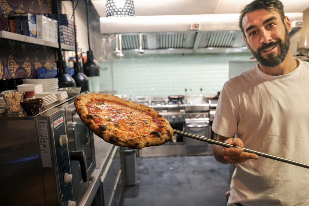 Pizzabakker van Tarantè 081 toont een versgebakken pizza in de keuken