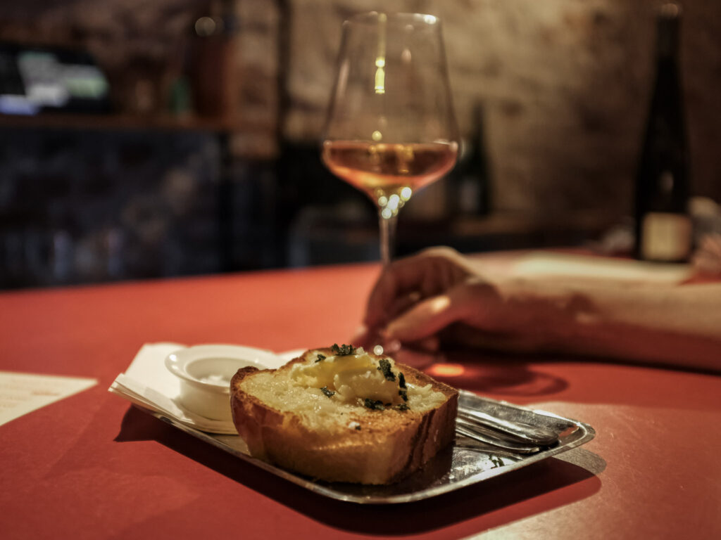 Glas natuurwijn en warm brood op een rood tafelblad bij Vin Natuur in Groningen