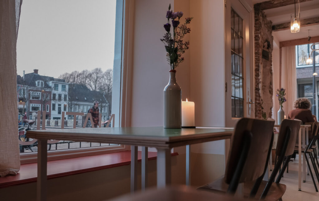 Tafel met bloemen en kaarslicht bij het raam van natuurwijnbar Vin Natuur in Groningen
