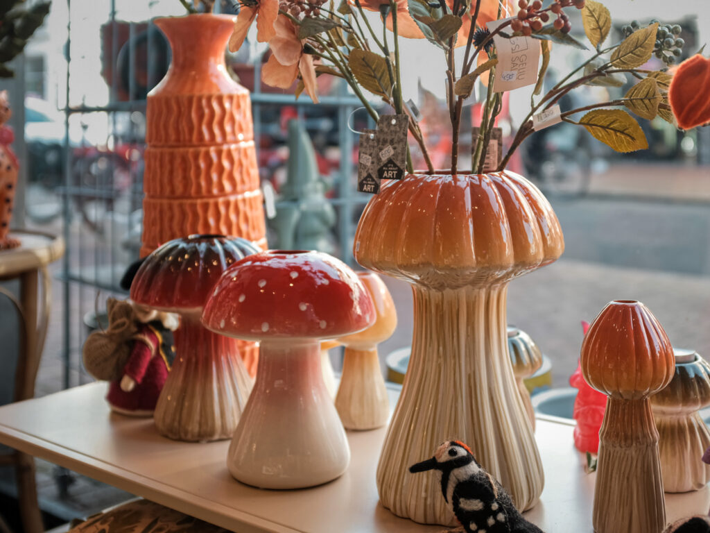 Herfstkleurige keramieken vazen, paddenstoelen en bloemen in de etalage van Walhalla